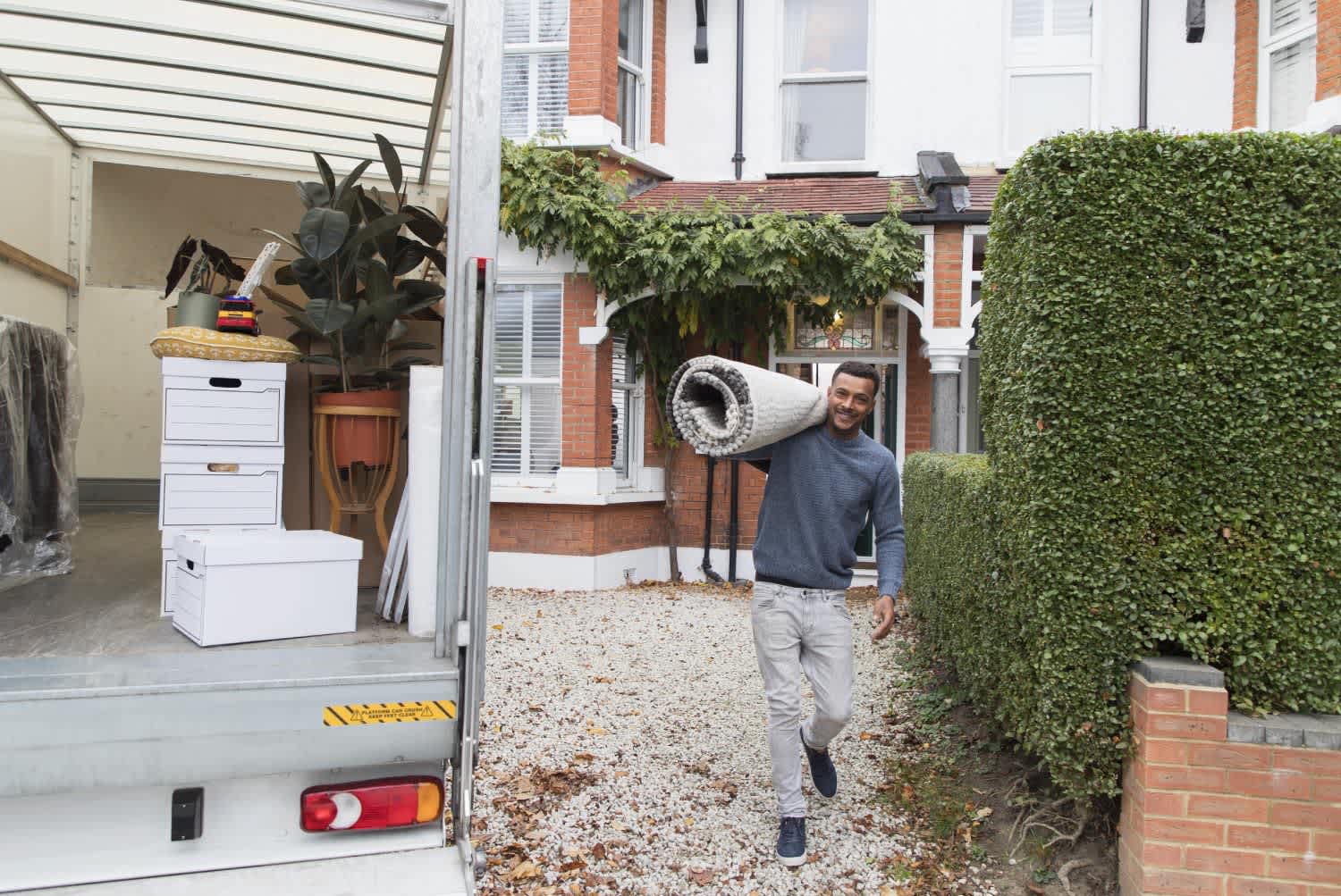 Man carrying rug moving out of house