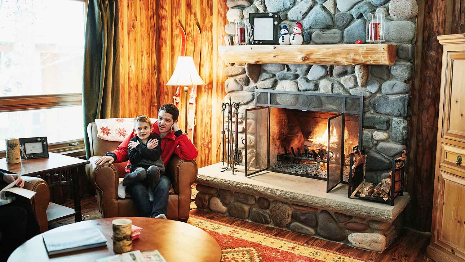 Father and son sitting by a stone fireplace