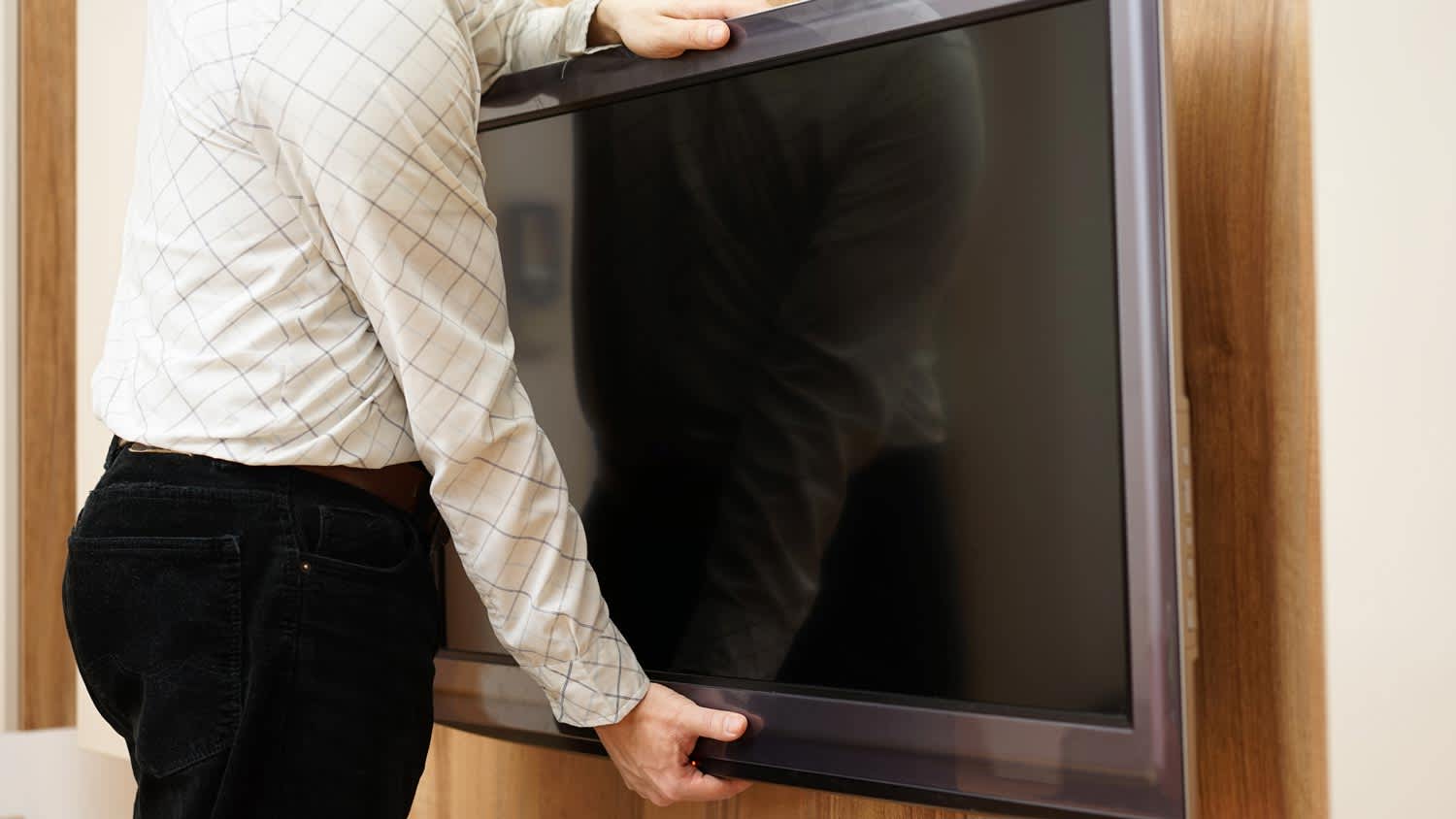 A man removing a TV off the wall