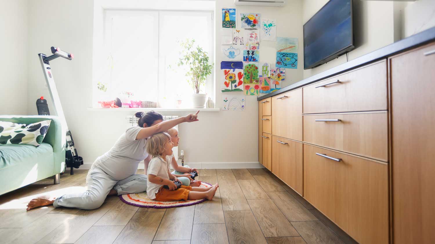 A mother with her kids sitting on the floor watching TV