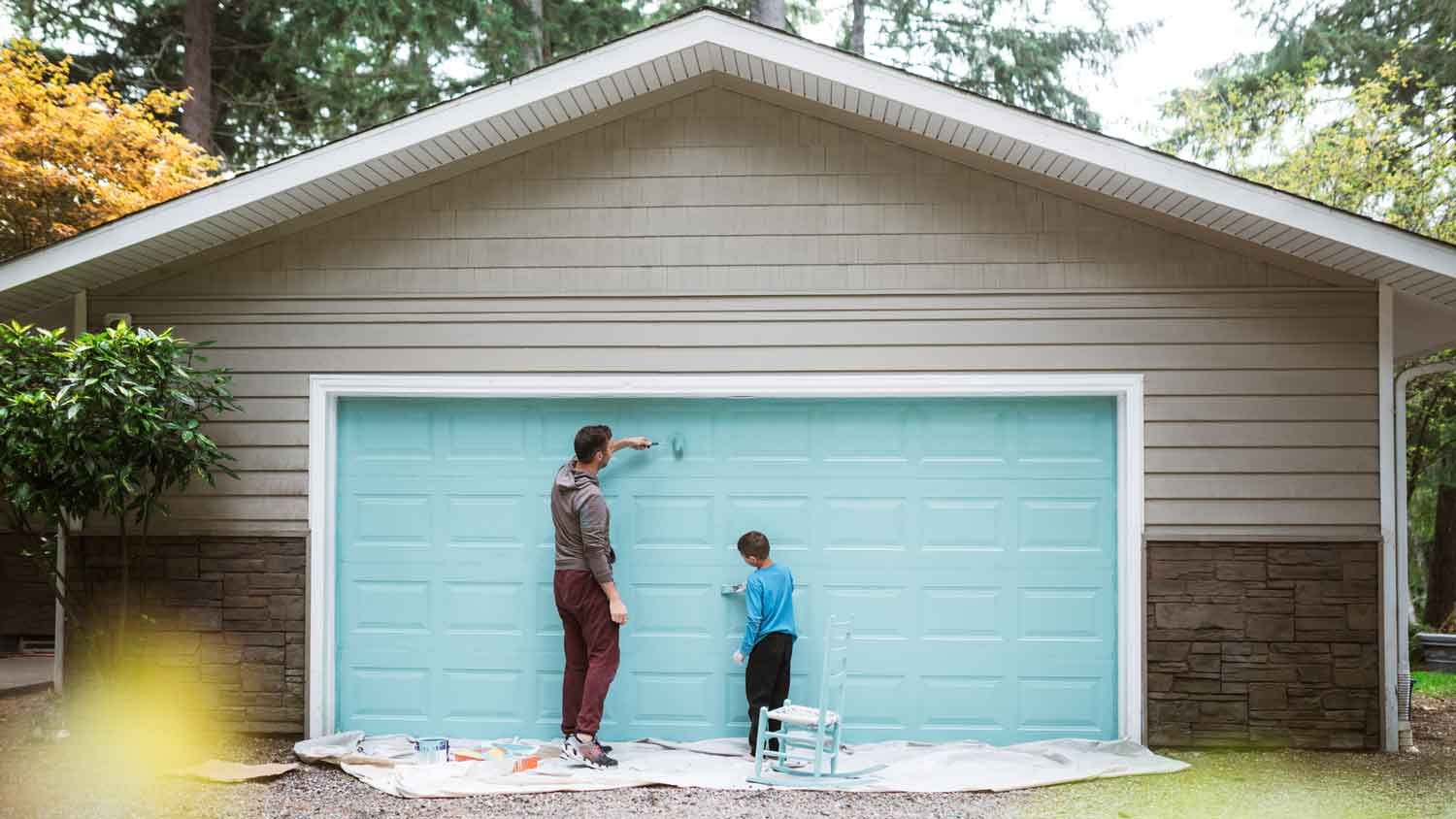 A father and his son painting a detached garage