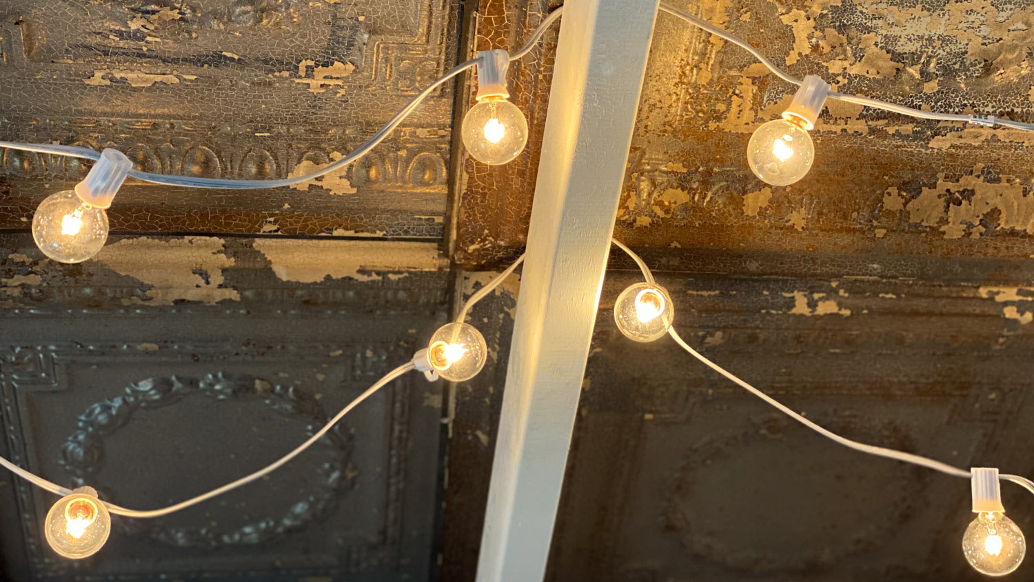 Illuminated string lights against an antique tile ceiling