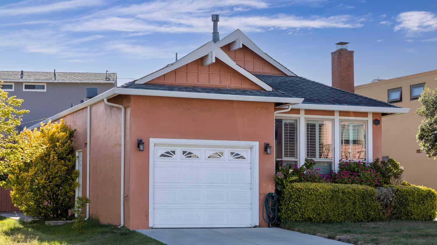 A white garage door of a pink painted house