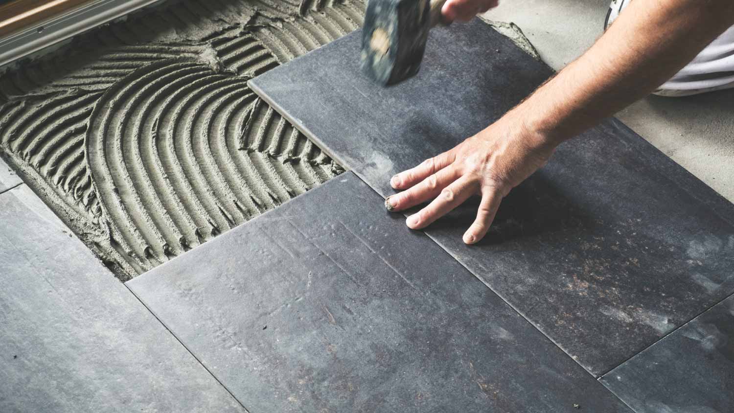 Worker placing ceramic floor tiles