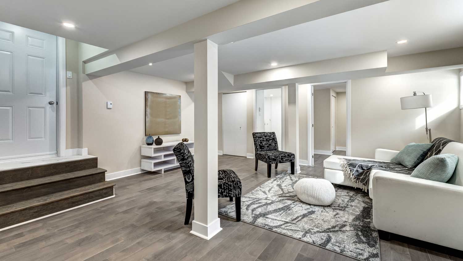 A living area in a basement with a support beam in the middle of it