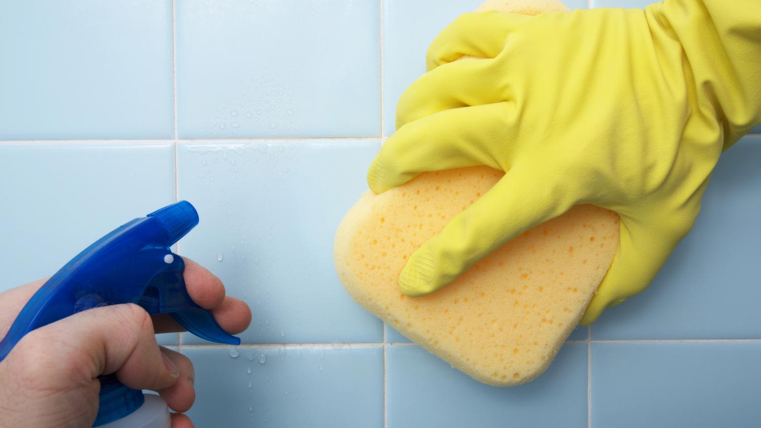 Close-up of a person softening the grout with a solution and a sponge