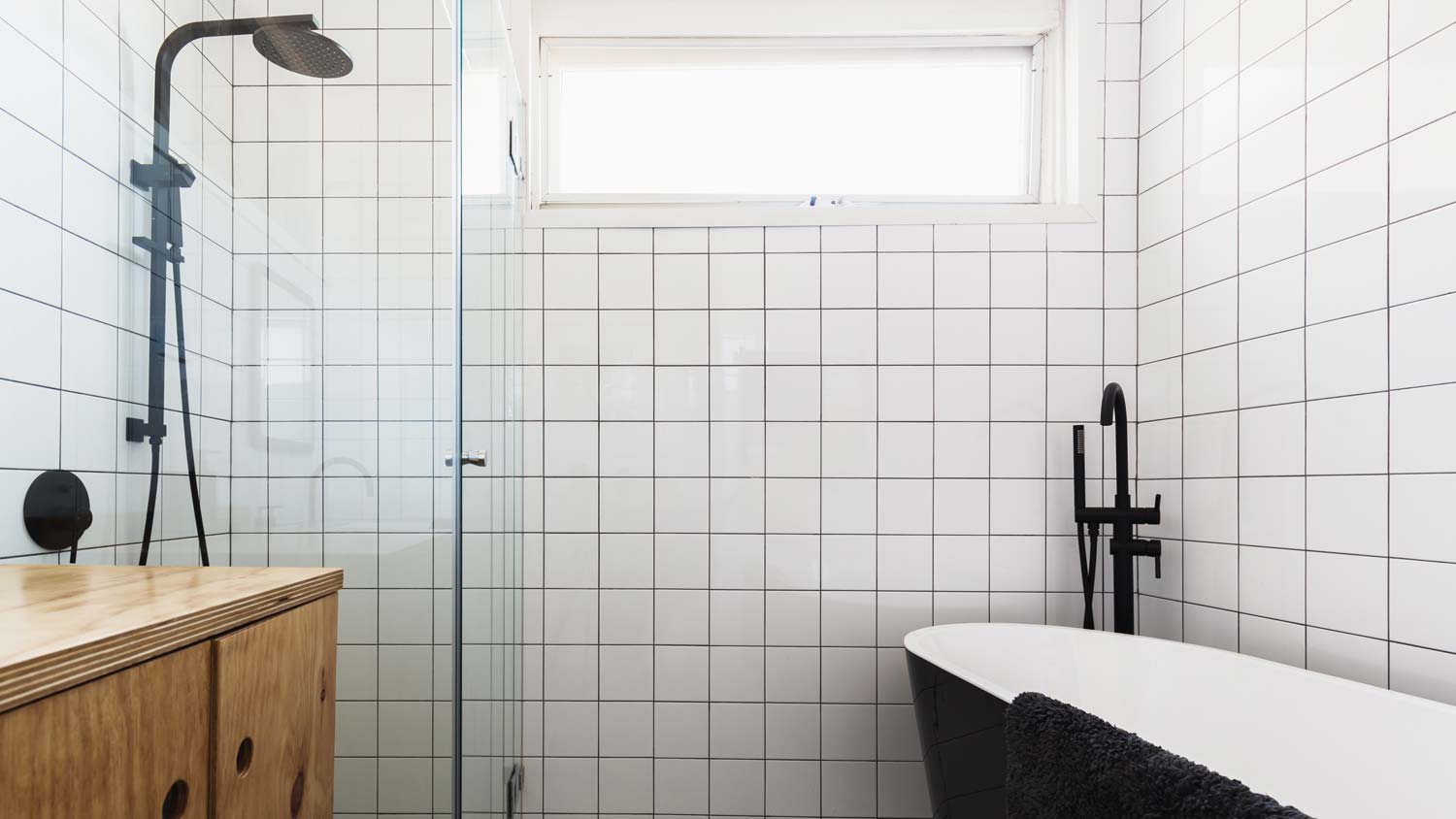 A minimal bathroom with dark grout and white square tiles