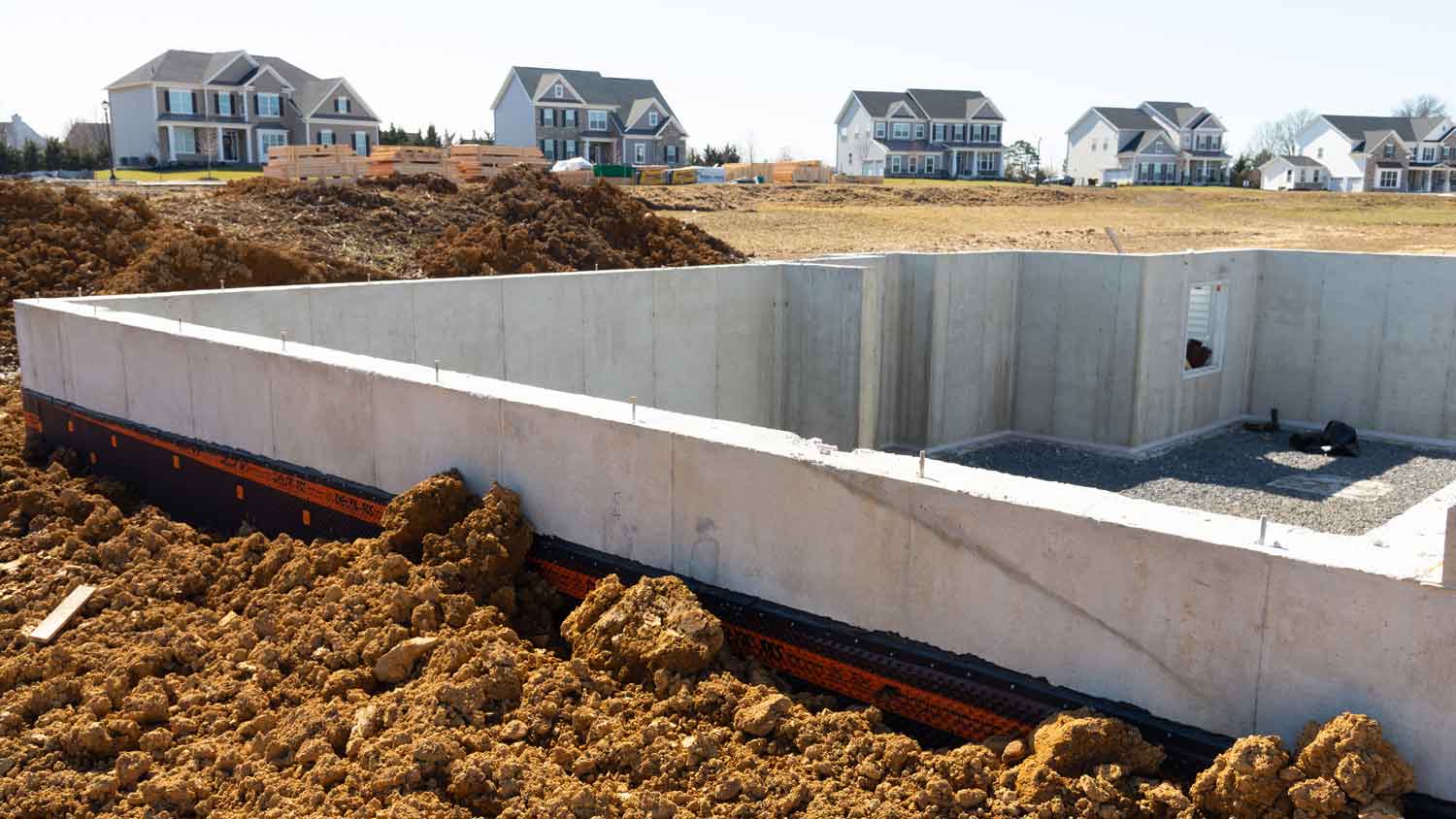 Foundation wall on construction site with completed houses in the background