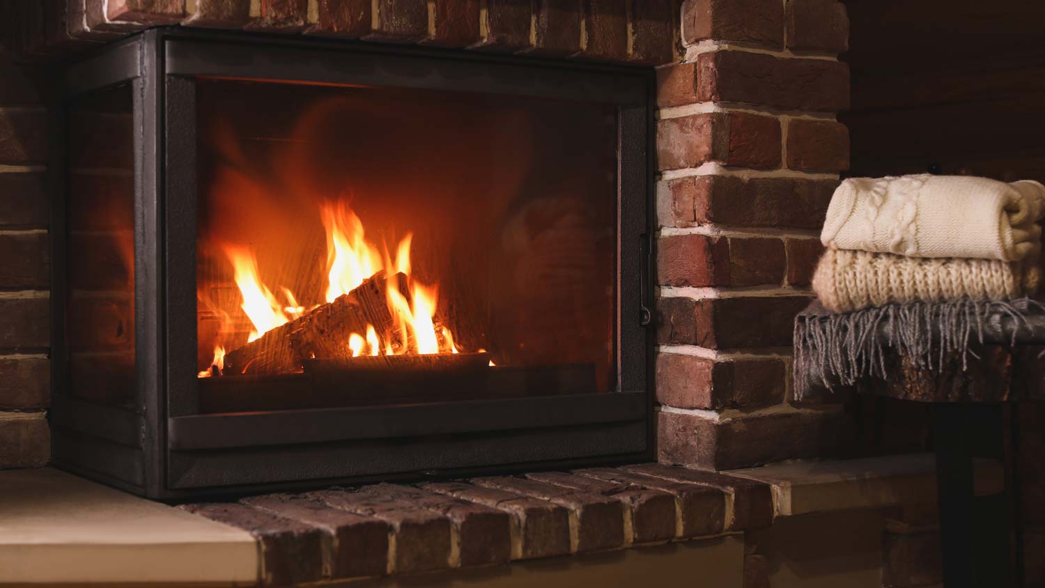 Stack of knitwear next to a fireplace with brick hearth
