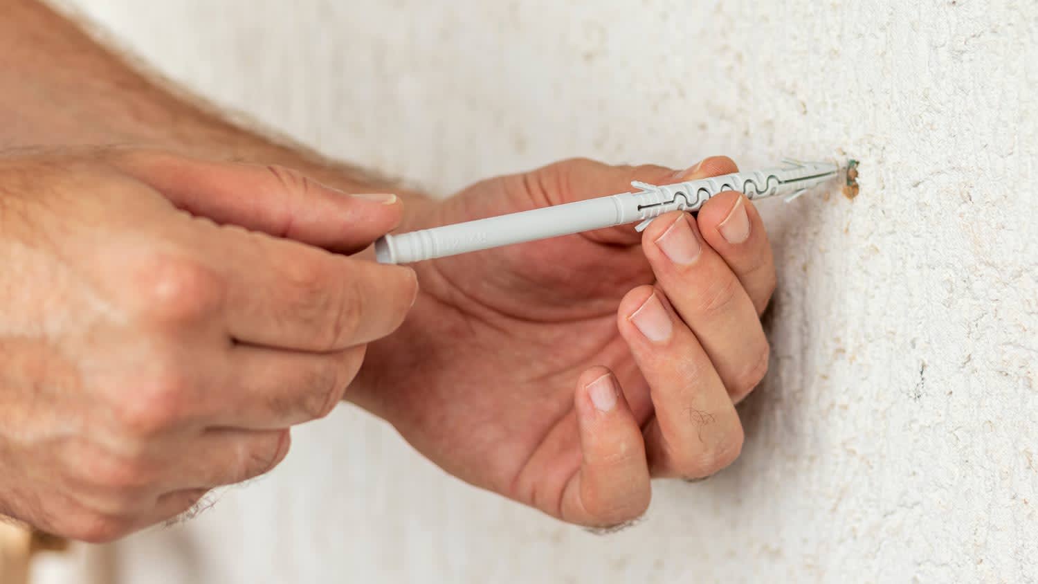 close up of man removing drywall anchor