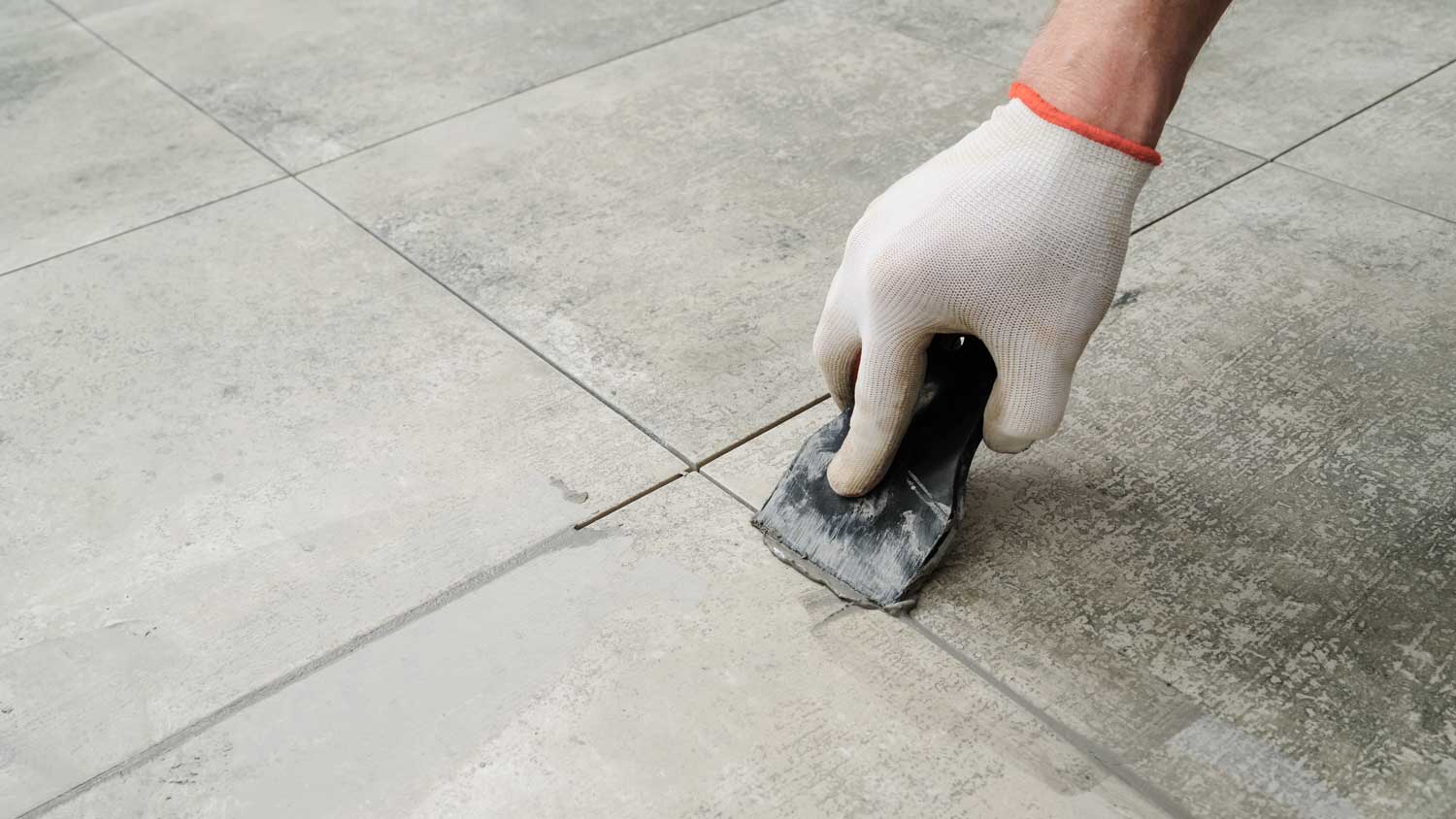 A person grouting stick and peel tiles