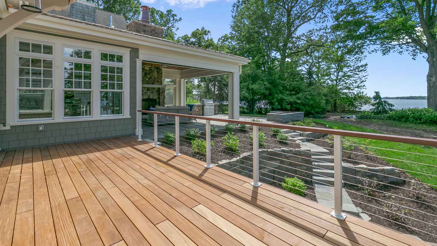 A large wooden deck on a beautiful house by the lake