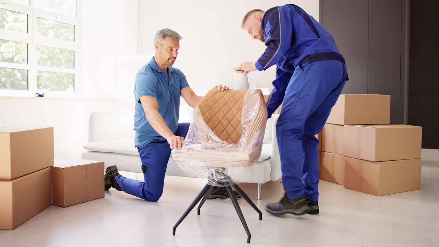 Professional movers wrapping a chair with plastic