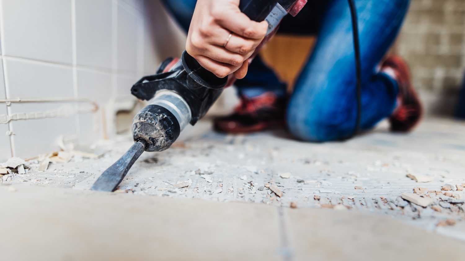 Woman removing old tiles, renovating the bathroom