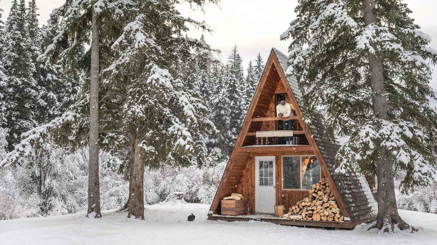 Man standing on a winter cabin balcony enjoying the view