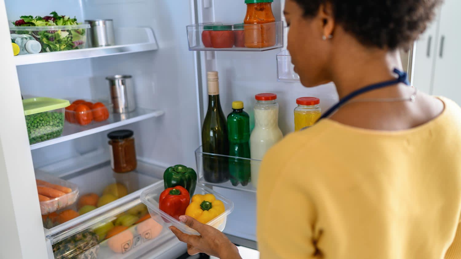 A woman looking at food in the refrigerator