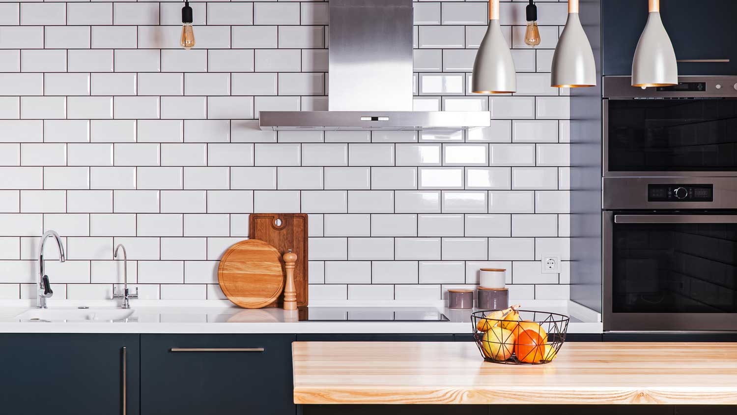 A kitchen with white tiles and dark grout