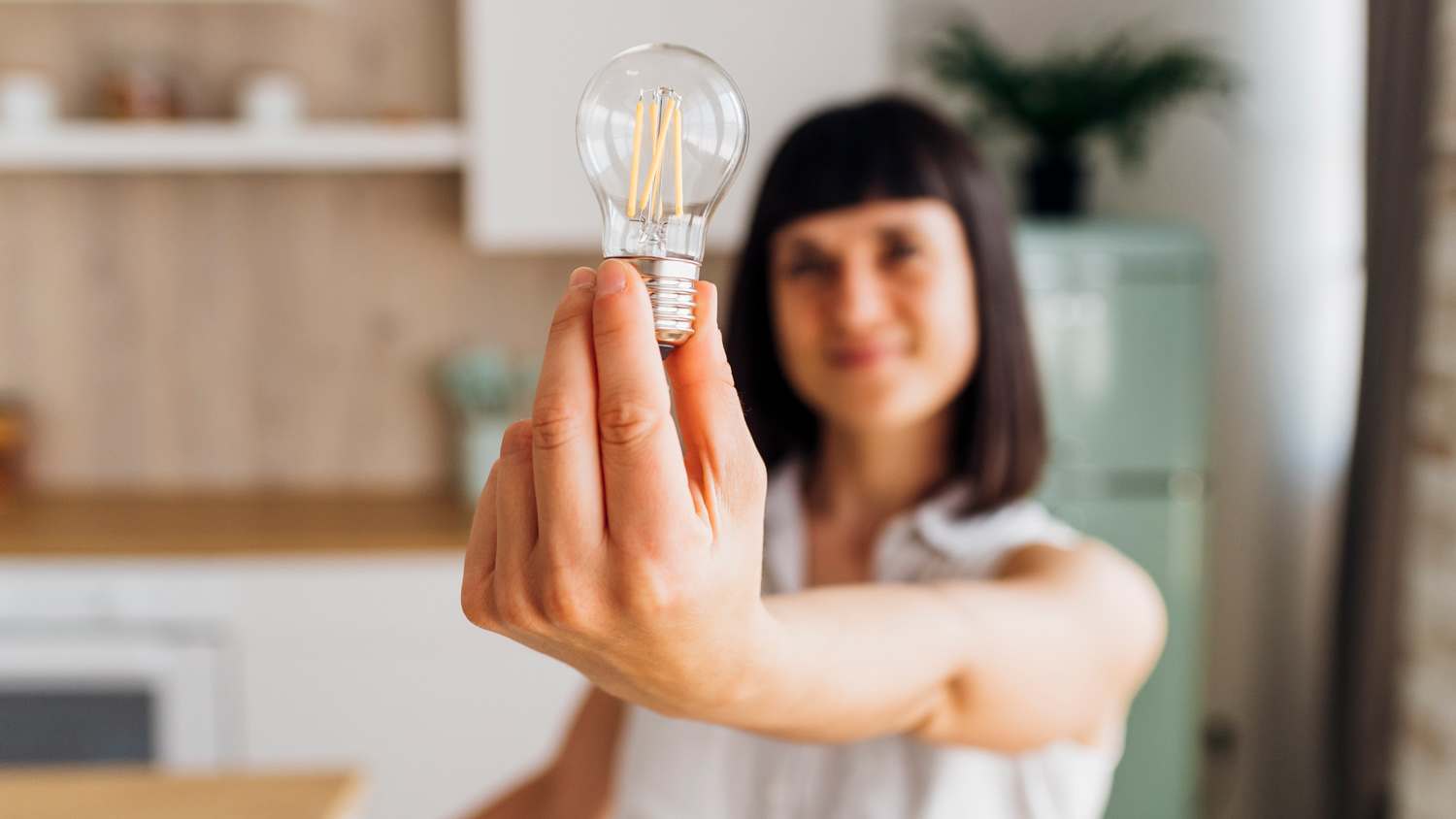 Woman holding light bulb at home