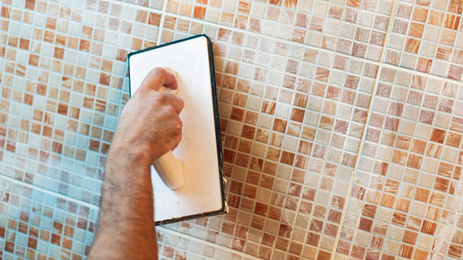 A person applying grout on ceramic tiles