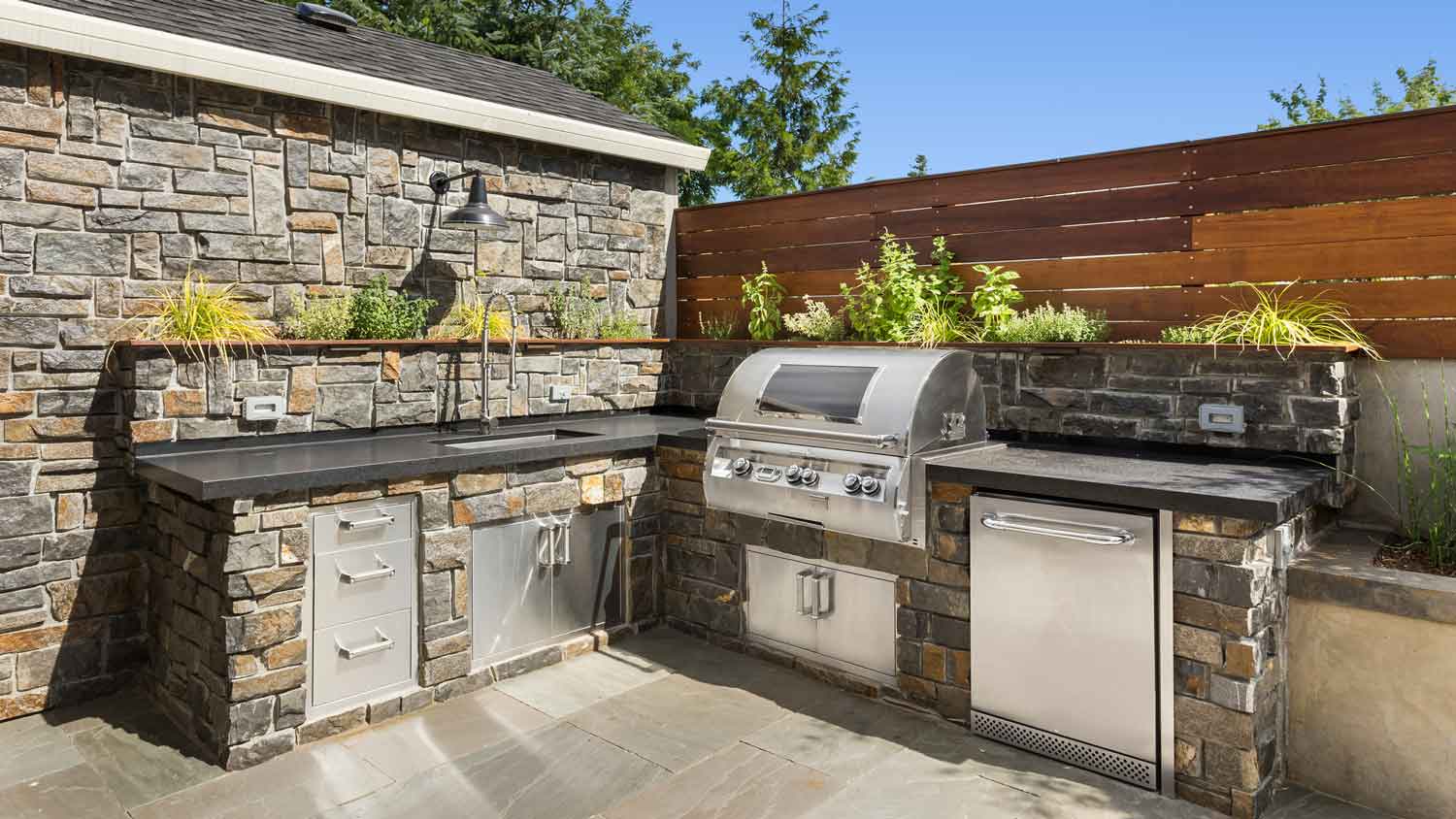 An L-shaped outdoor kitchen in a beautiful backyard