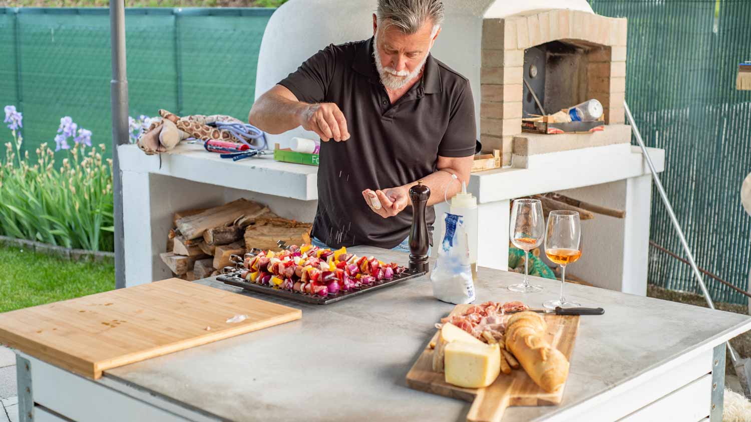 A mature man preparing barbecue in a freestanding outdoor kitchen