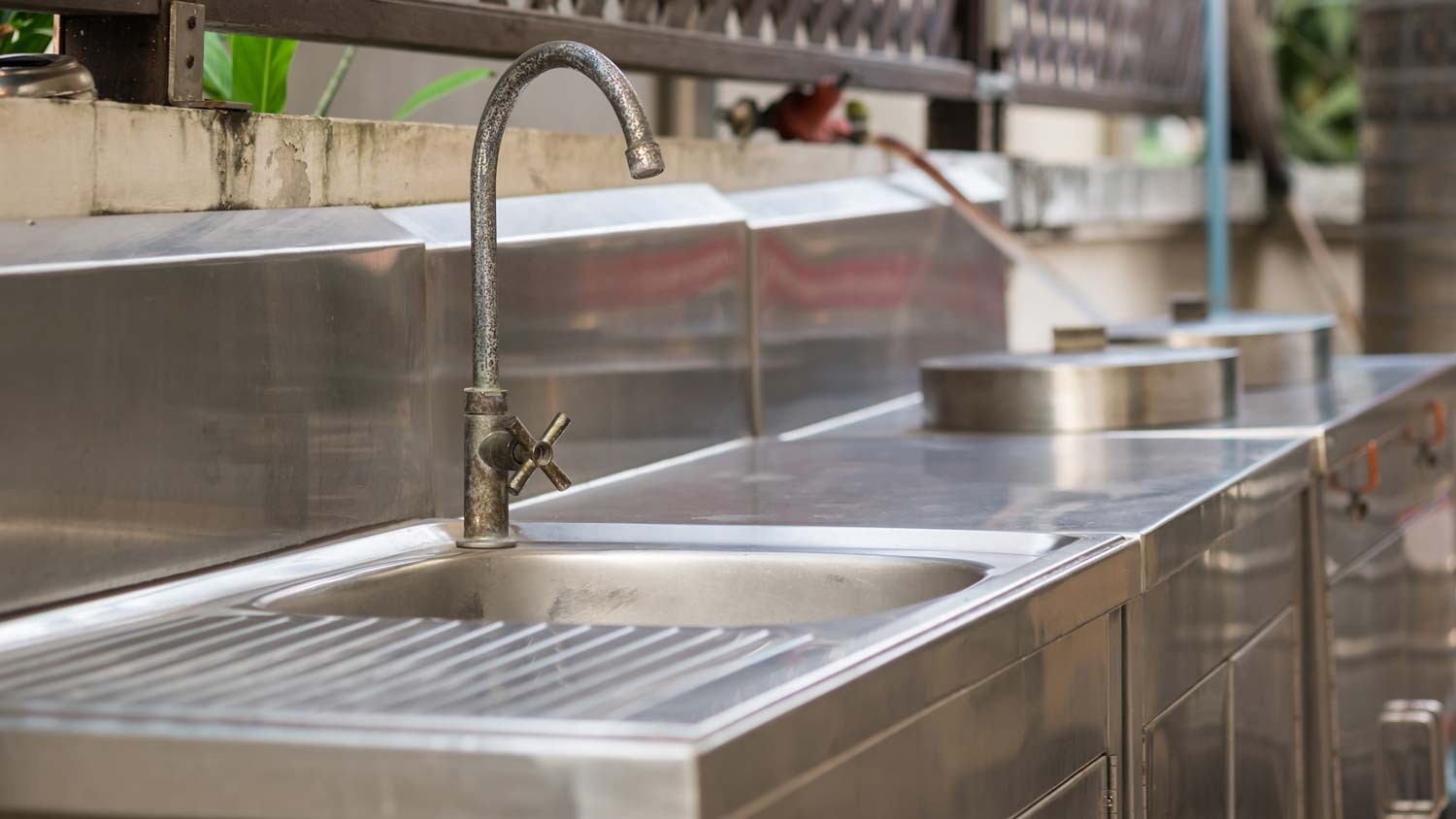 An outdoor kitchen with a stainless steel counterop and sink
