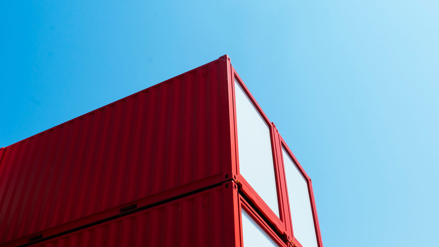 A red shipping container against the blue sky