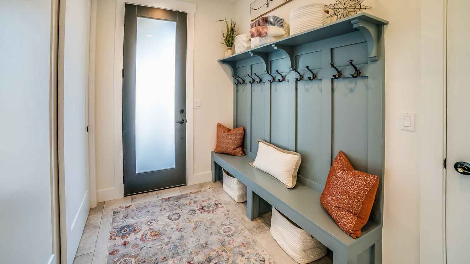 Home mudroom with blue bench area rug and pillows