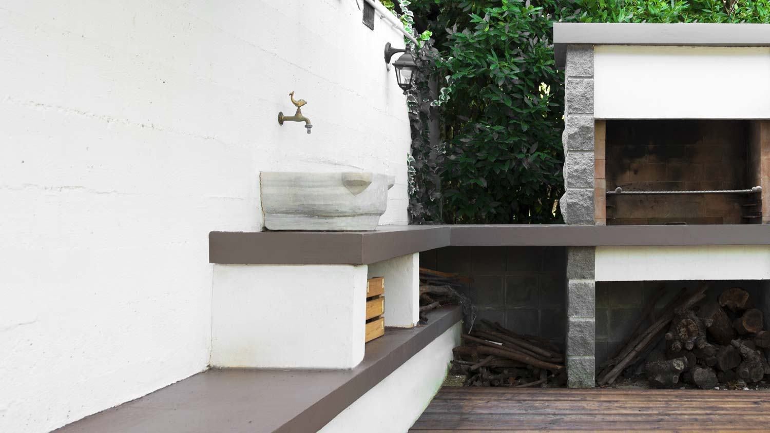 A stone sink next to a grill in an outdoor kitchen