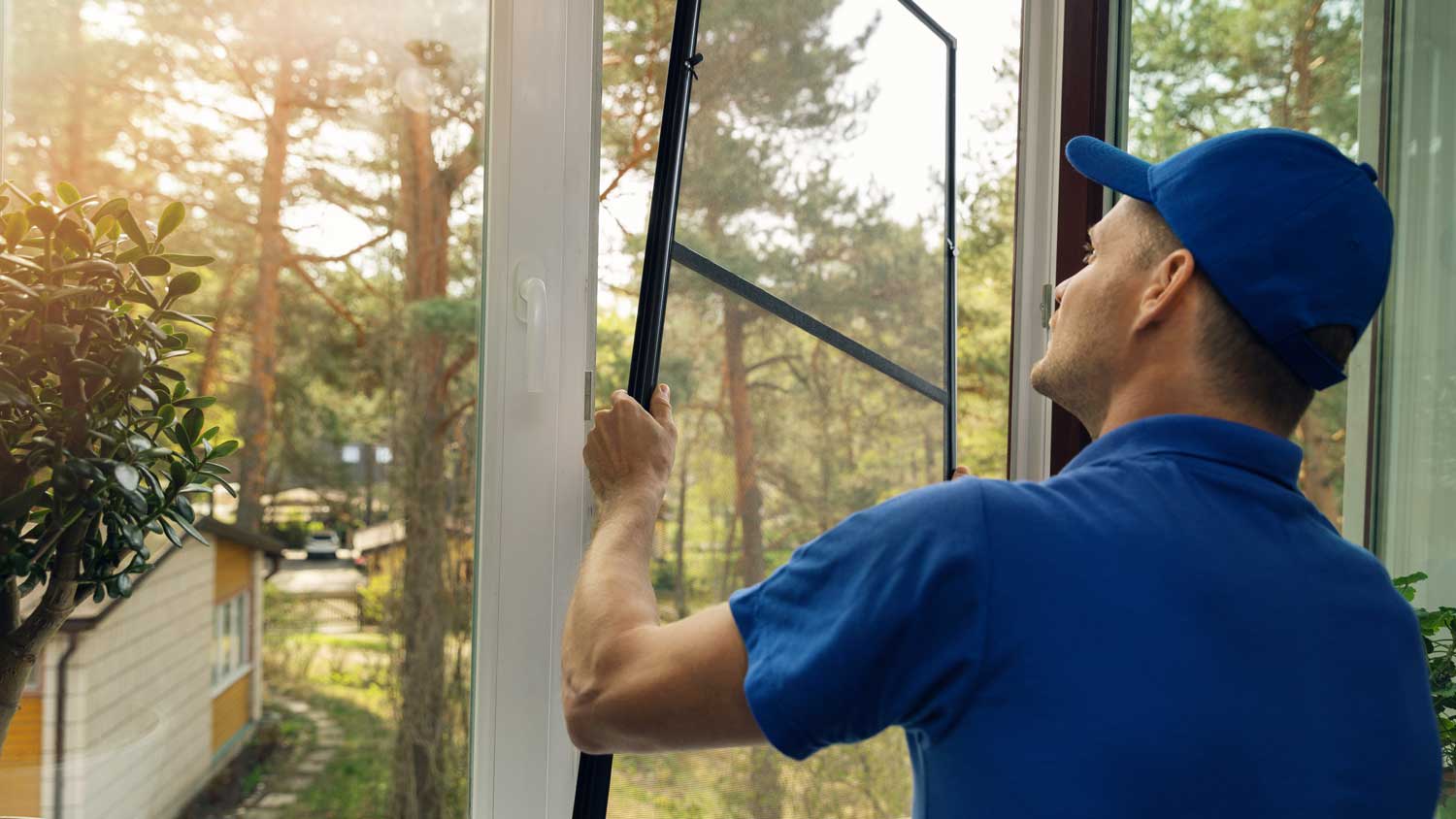 A worker installing a fiberglass window screen