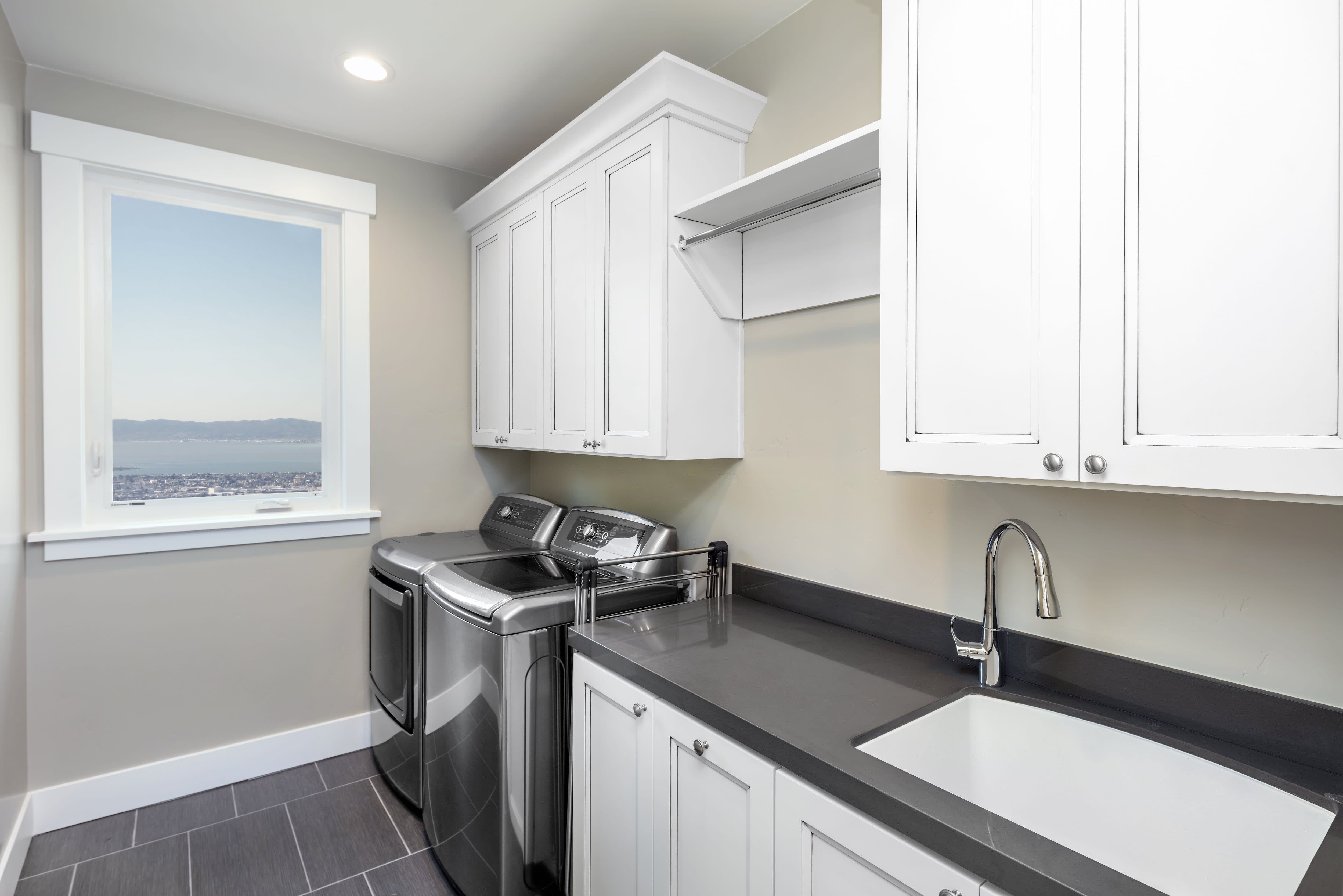 A mudroom with laundry units, counter space, shelving, and a sink