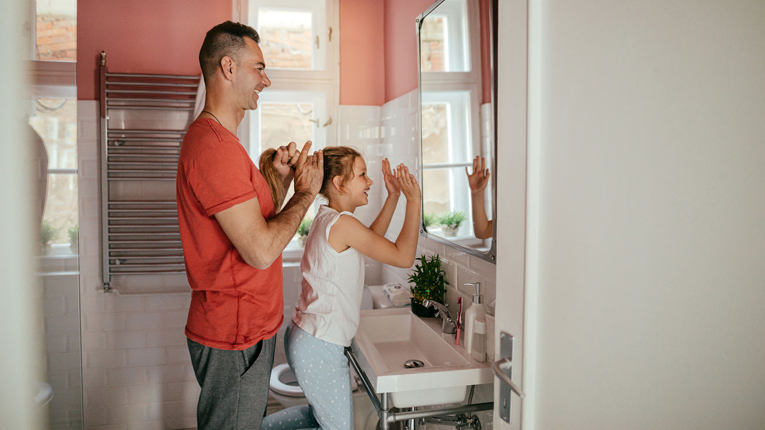 Father puts his daughter's hair in a ponytail