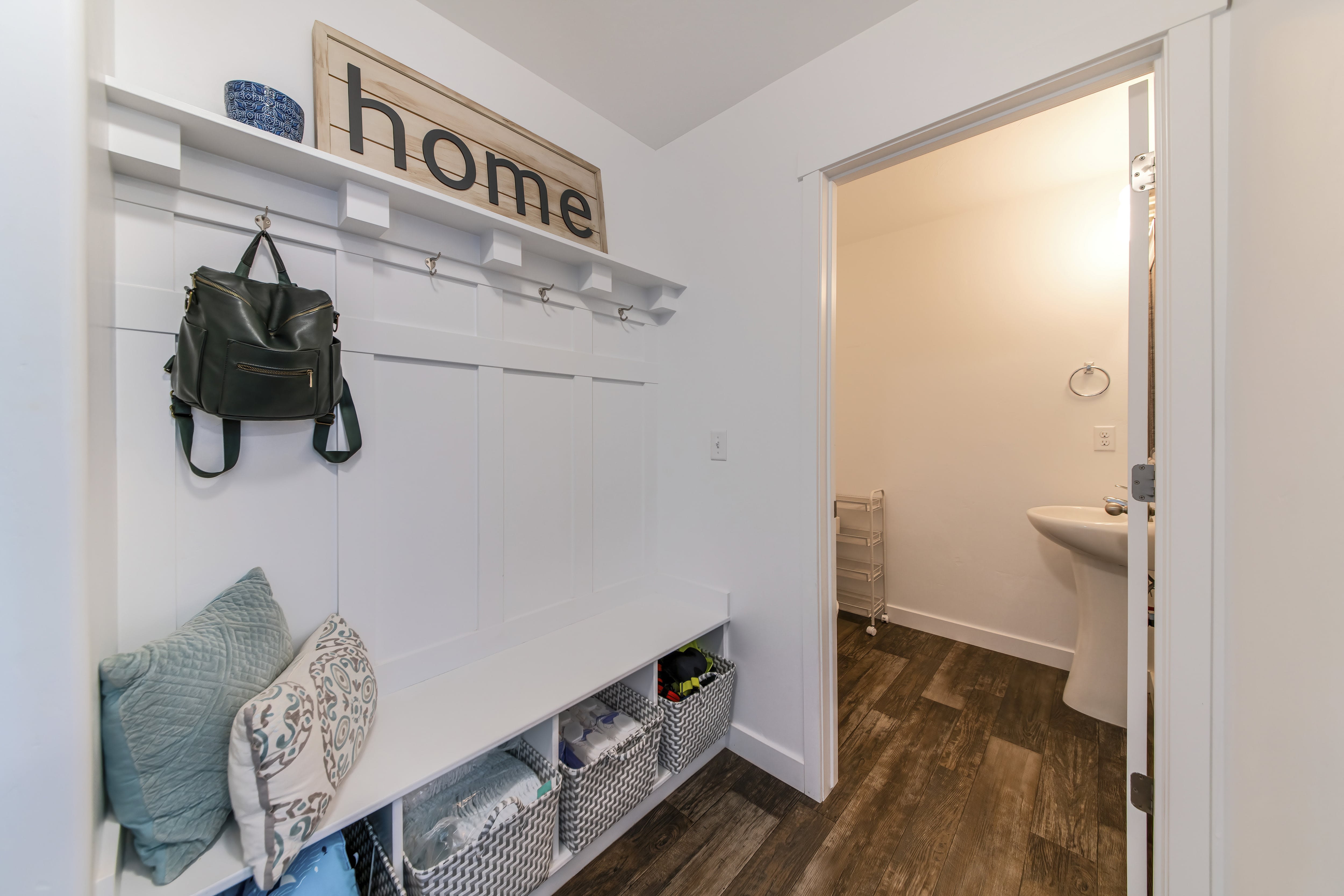 A white mud room with backpack hooks and a built in bench