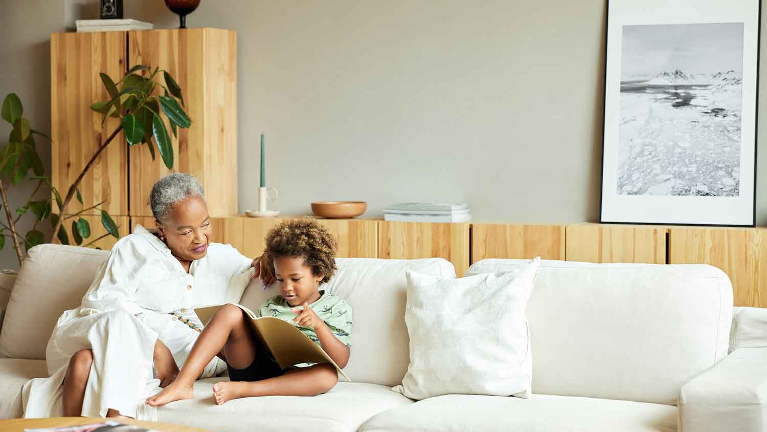 Grandmother and grandson sitting on the couch reading a book