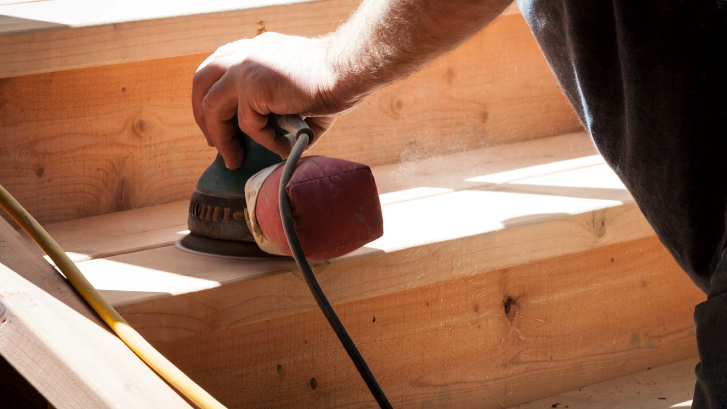 man sanding down stairs