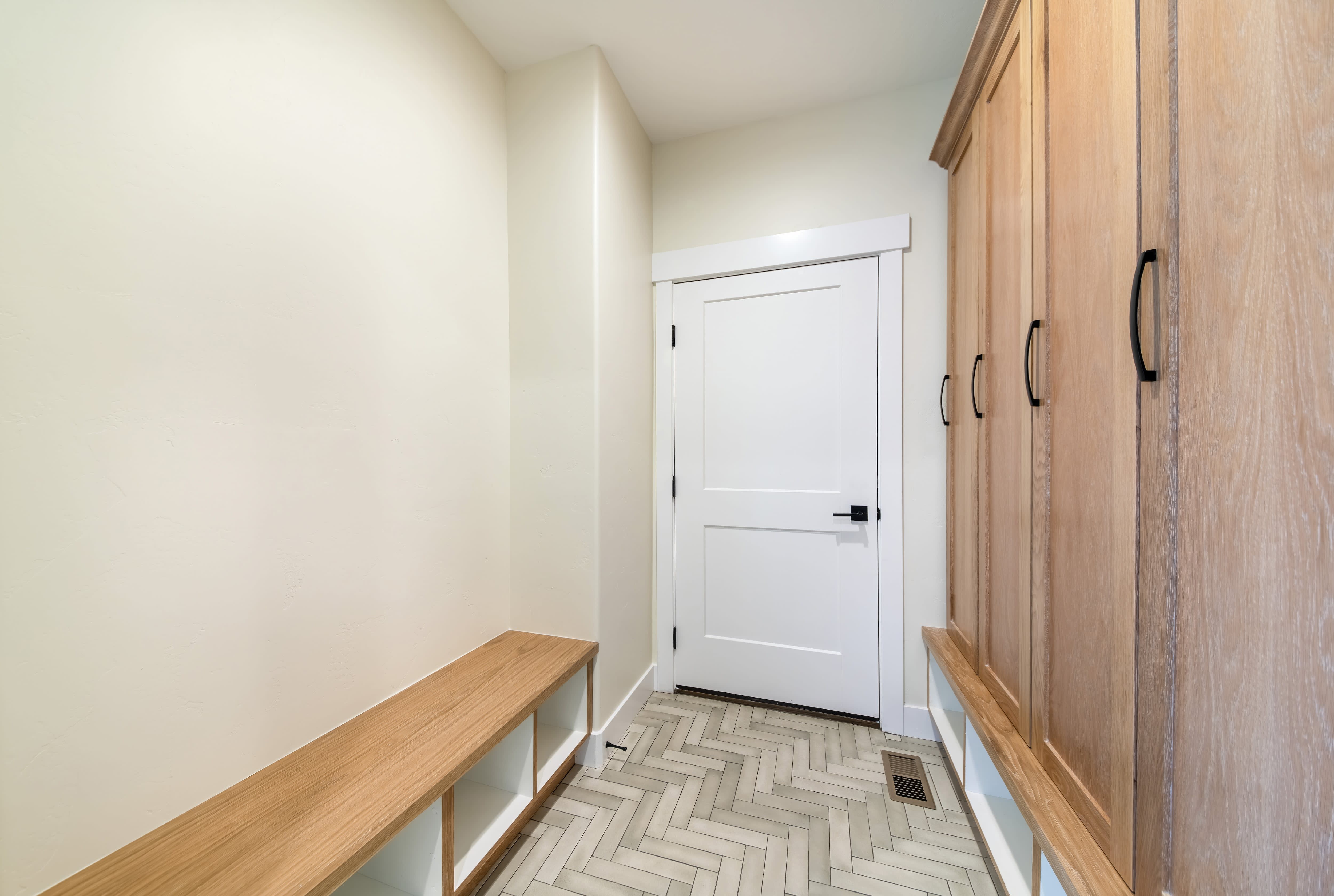 A laundry room with herringbone tile and built-in cabinets