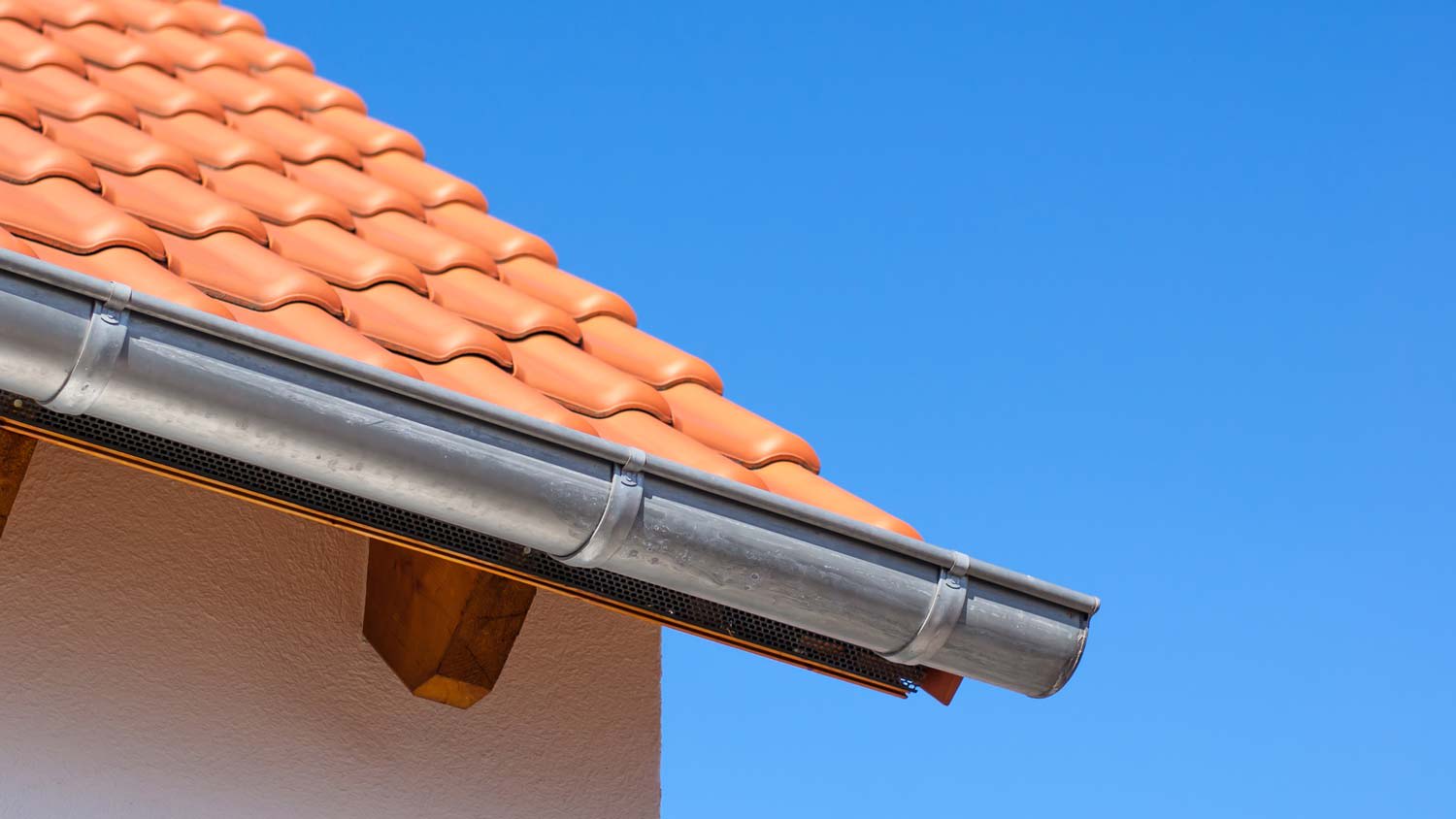 Detail of a tiled roof and gutters against the blue sky