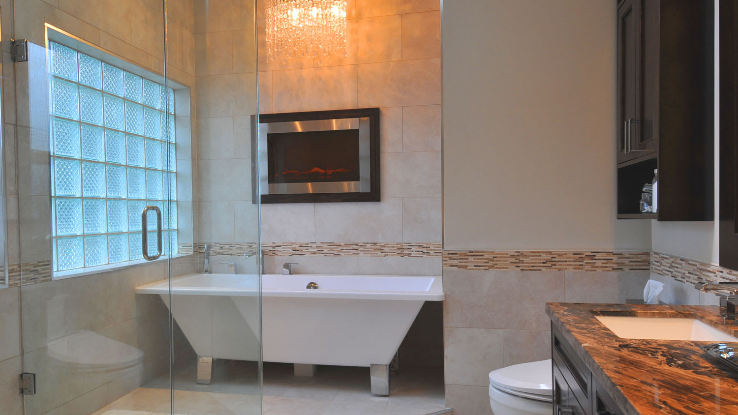 The interior of a luxurious bathroom with glass block windows and a chandelier