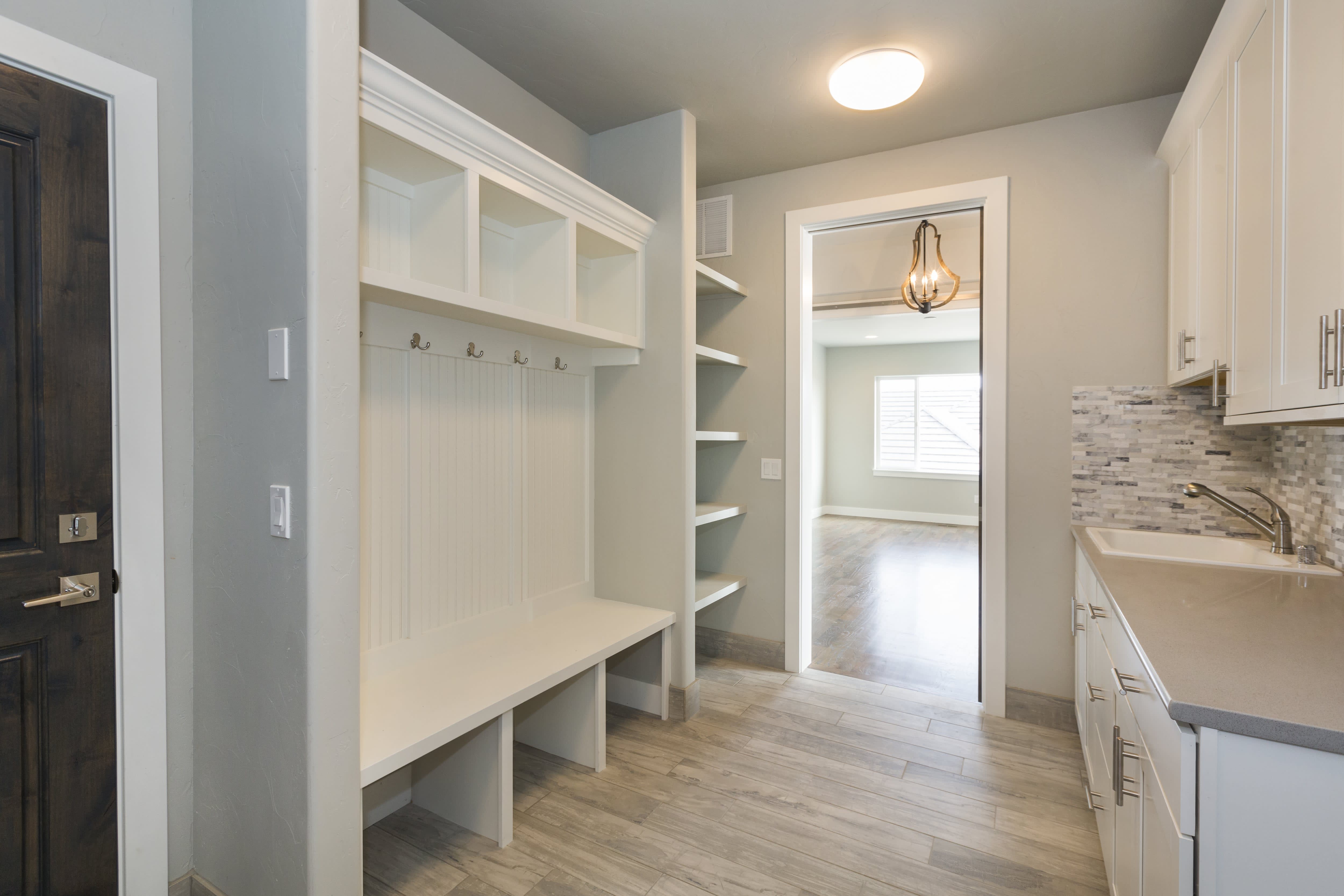 A luxury mudroom with a sink, countertops, shelving, and cubbies