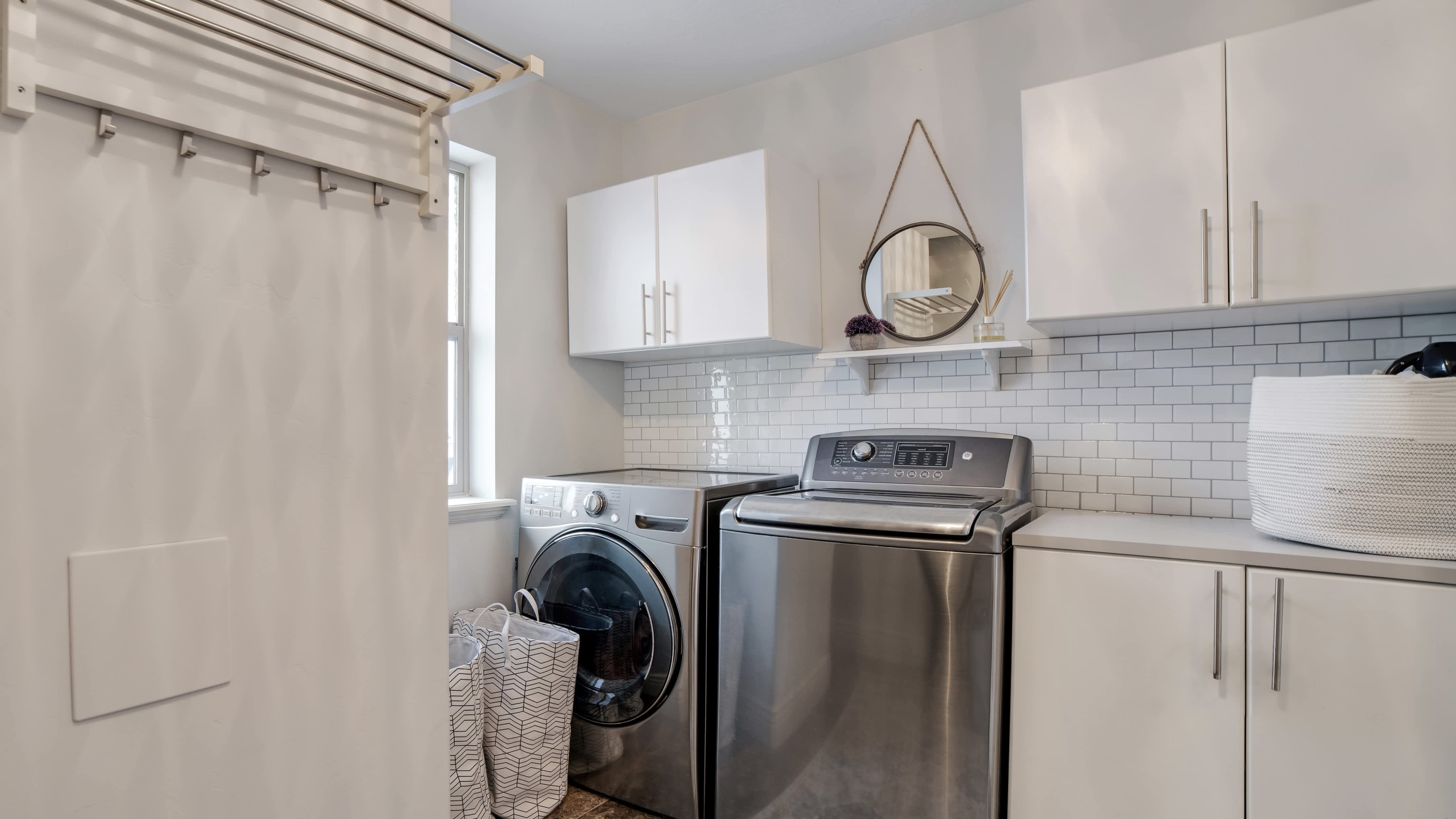 A mudroom with a washer, dryer, and tile backsplash
