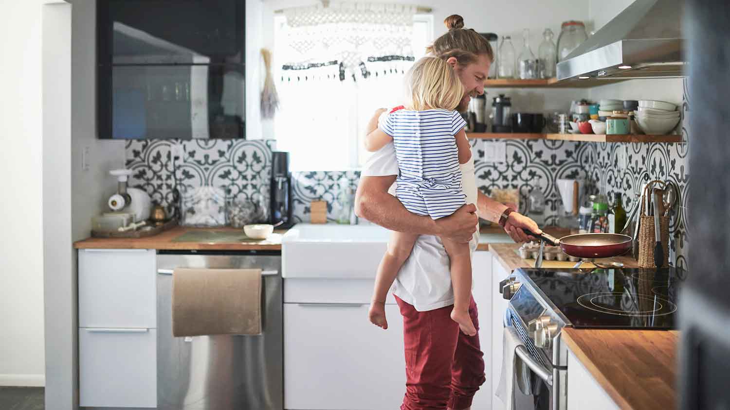 Father holding daughter and cooking a meal in the kitchen