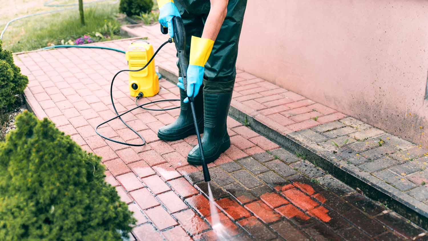 man cleaning pavement with high pressure water cleaner