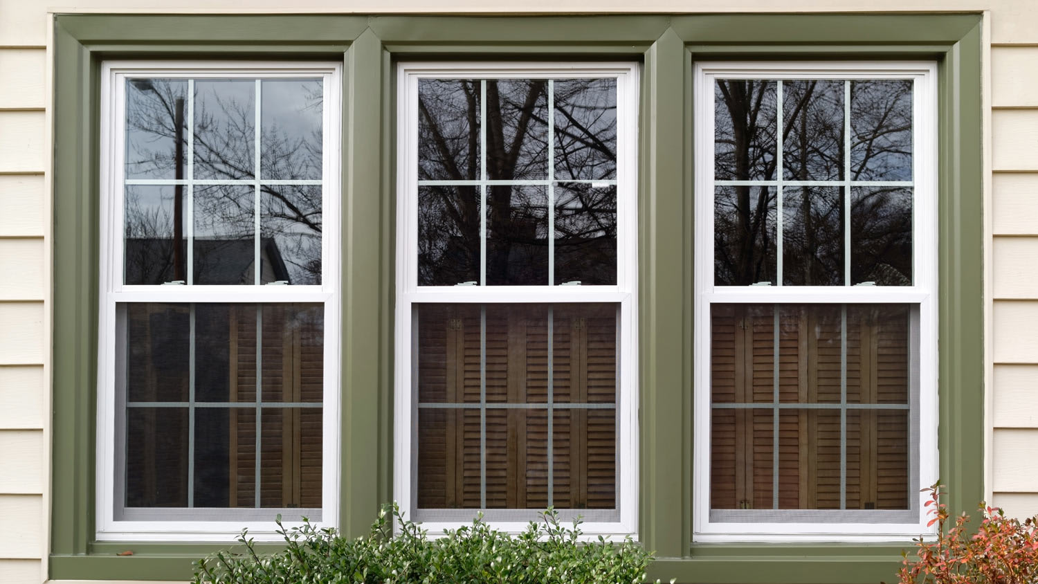 Three new replacement windows with green trim on front of house