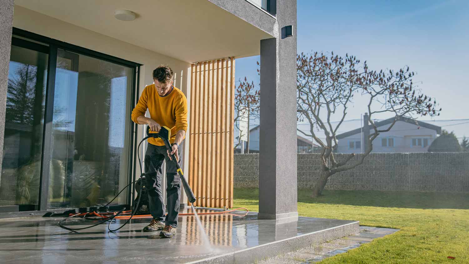 Man using pressure washer to clean concrete patio
