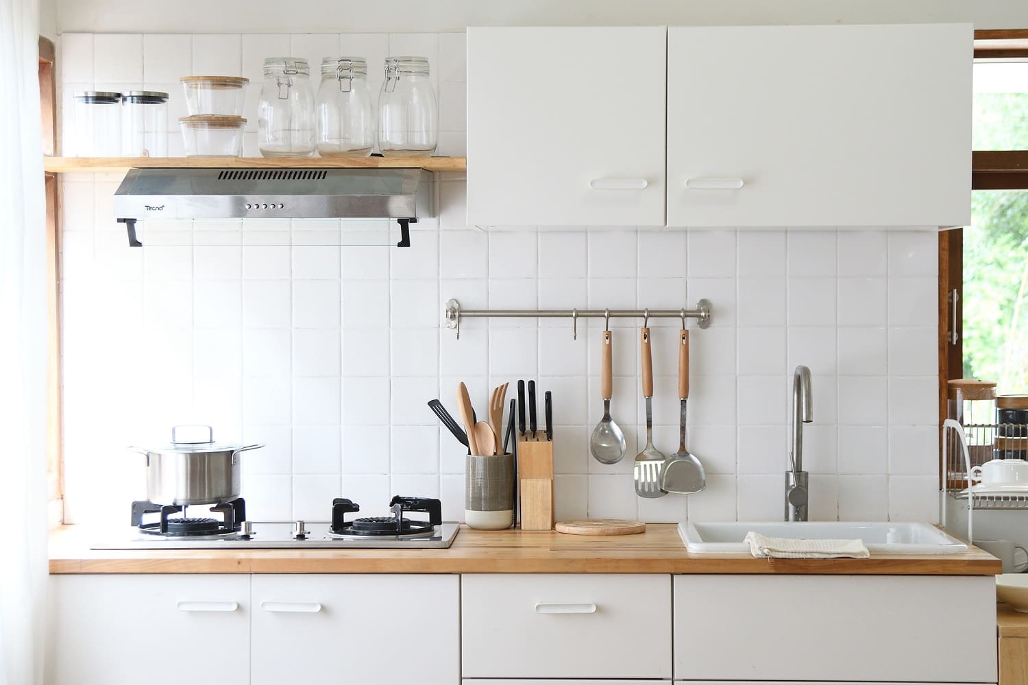A modern kitchen with white cabinets and wooden countertop