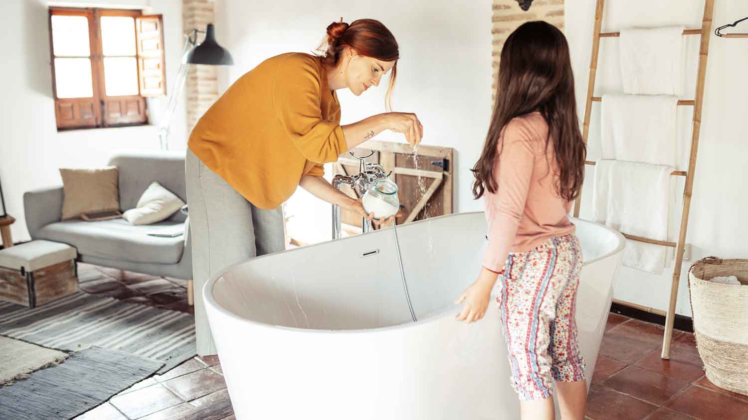 Woman sprinkling bath salts into a bathtub