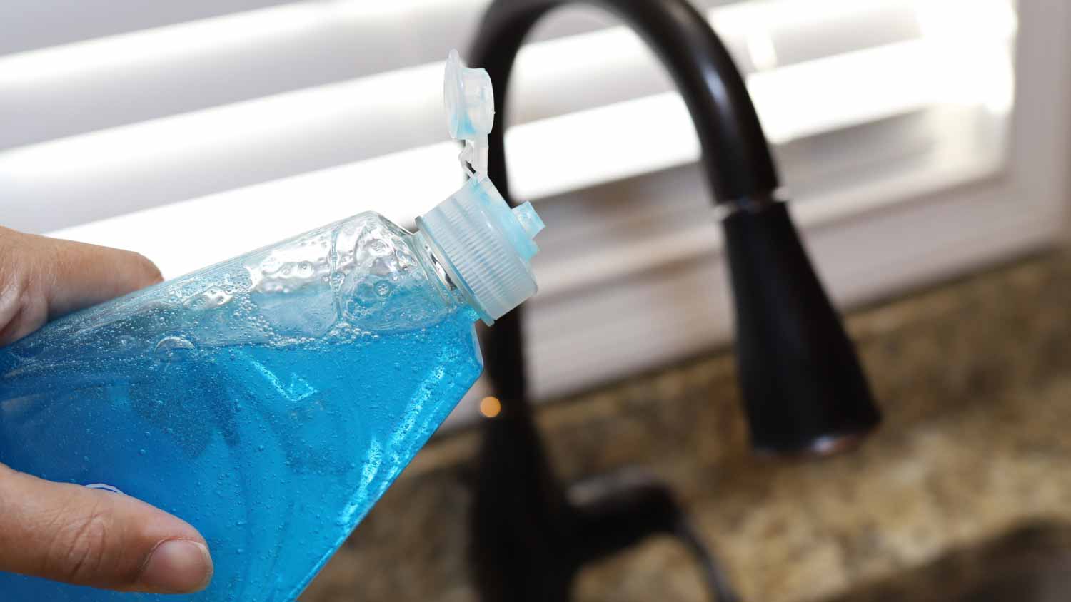 A woman holding a bottle of dish detergent