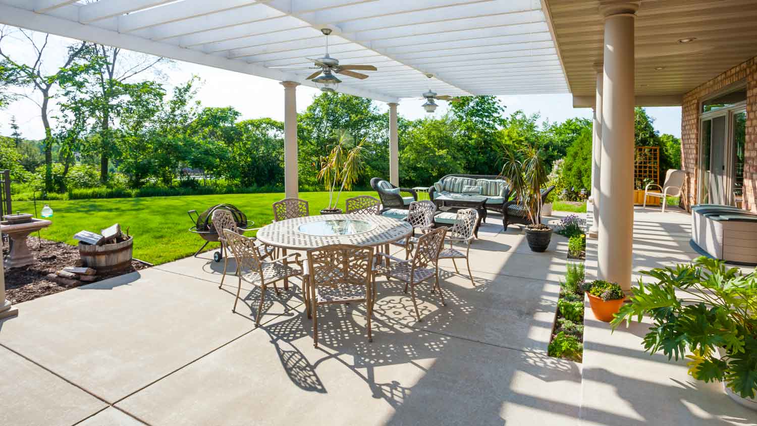 A concrete patio with various furniture and a pergola