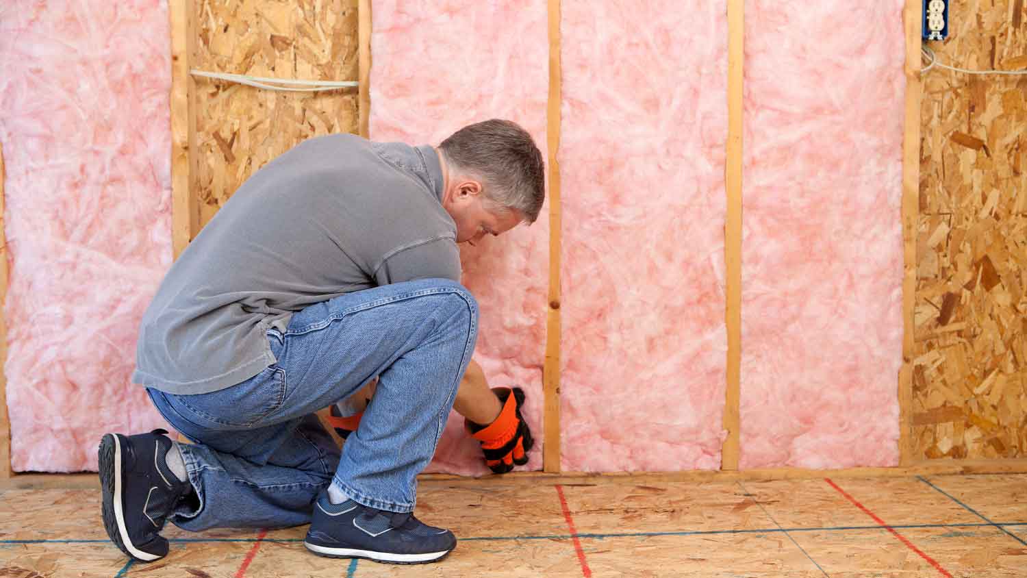 Handyman installing fiberglass batt insulation