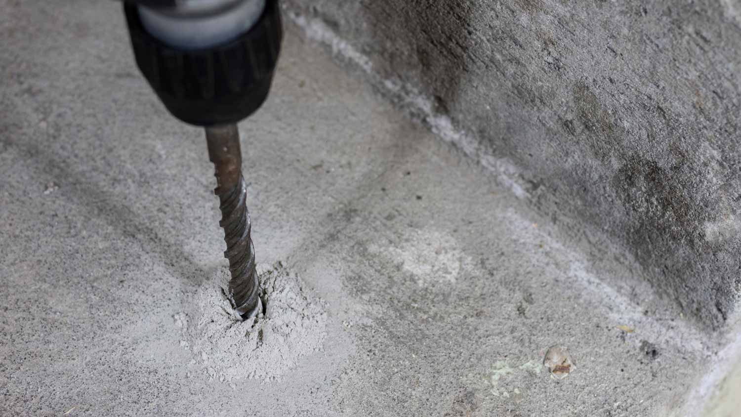 Close-up of a person drilling a hole in a concrete slab